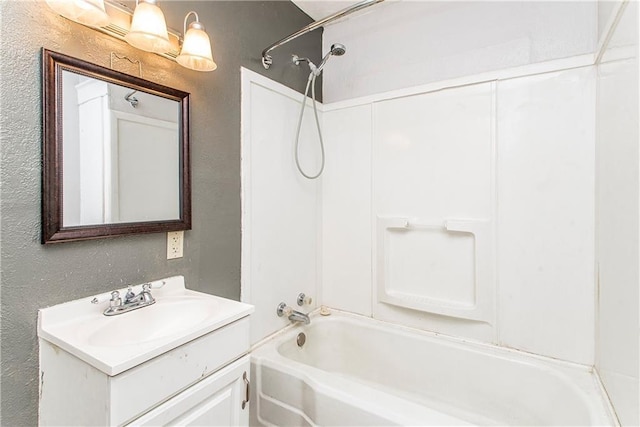 bathroom featuring vanity, bathing tub / shower combination, and a textured wall