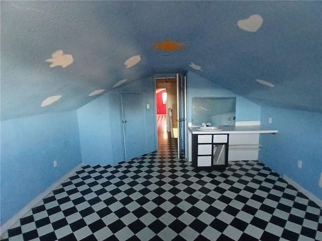 bonus room with sink, a textured ceiling, and vaulted ceiling