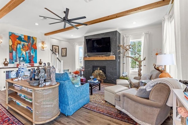 living room with beamed ceiling, hardwood / wood-style floors, ceiling fan, and a high end fireplace