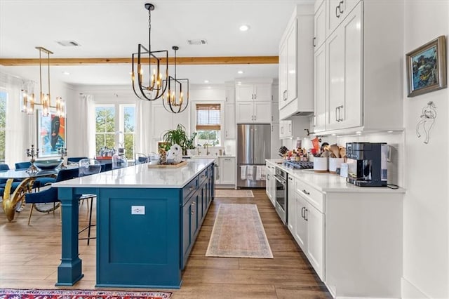 kitchen with a kitchen island, white cabinetry, hanging light fixtures, and appliances with stainless steel finishes