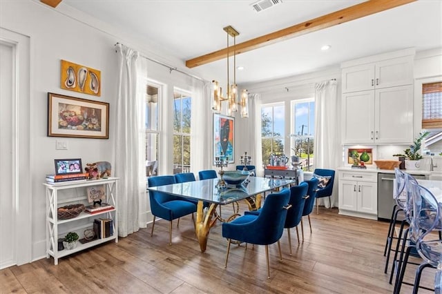 dining area featuring beam ceiling, light hardwood / wood-style floors, and a chandelier