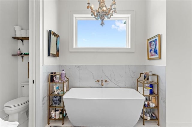 bathroom with toilet, a tub to relax in, and a chandelier