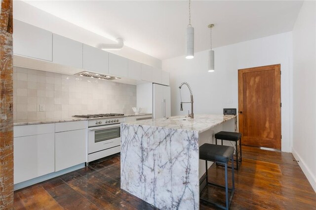 301 S Toulme St Unit 108, Bay Saint Louis, MS 39520 - kitchen with backsplash, white cabinets, dark hardwood / wood-style floors, and high end appliances