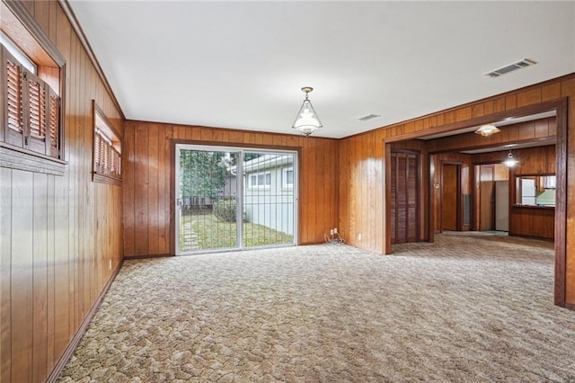 carpeted empty room featuring wood walls