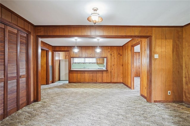 unfurnished living room with light colored carpet, ornamental molding, and wooden walls