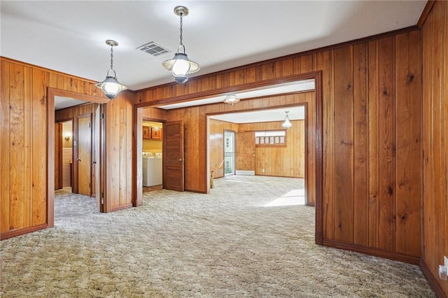 carpeted empty room with washer / clothes dryer and wood walls