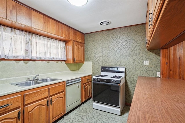 kitchen with stainless steel dishwasher, ornamental molding, sink, and white gas stove