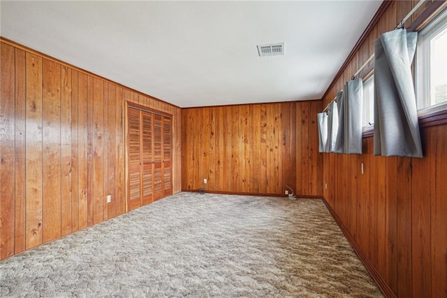 spare room featuring carpet flooring and wood walls