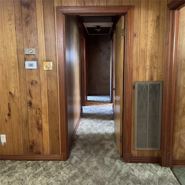 hallway with wooden walls and light colored carpet