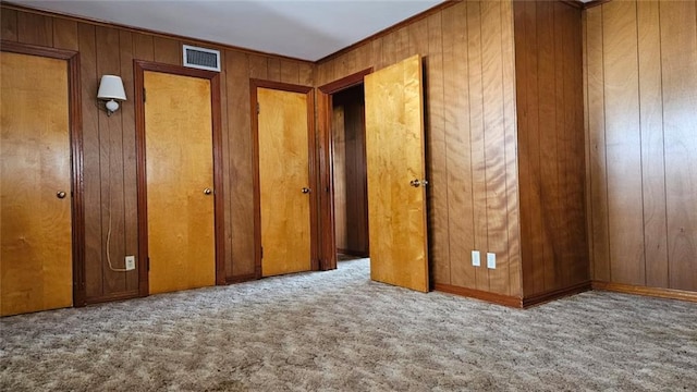 interior space featuring light carpet, wooden walls, and ornamental molding