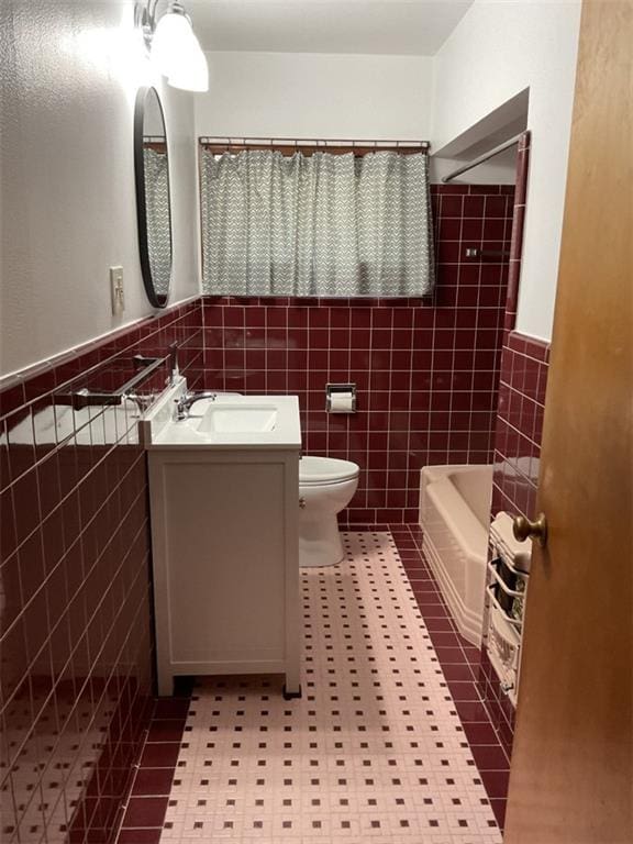 full bathroom featuring shower / bath combo with shower curtain, vanity, toilet, and tile walls