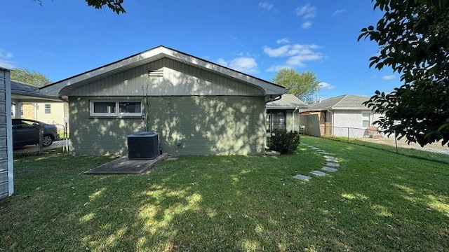 rear view of property featuring cooling unit and a lawn