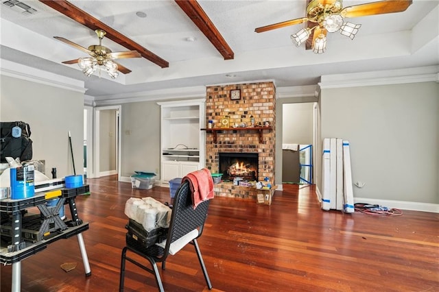 living room featuring a raised ceiling, dark hardwood / wood-style flooring, ornamental molding, and a brick fireplace