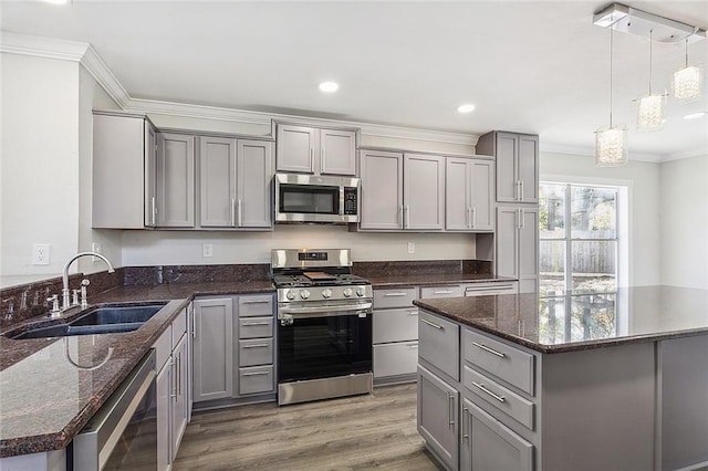 kitchen featuring dark stone counters, hanging light fixtures, sink, gray cabinets, and appliances with stainless steel finishes