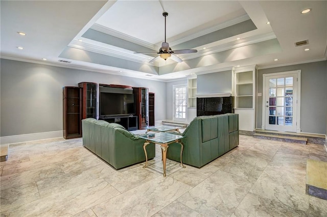 living room with a raised ceiling, ceiling fan, and crown molding