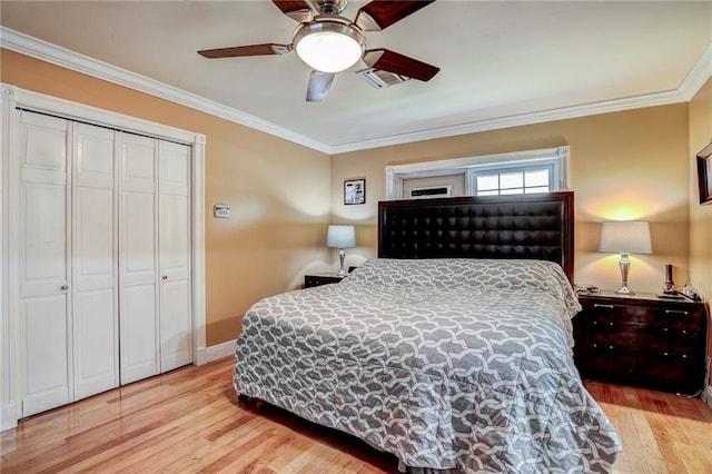 bedroom featuring light wood-type flooring, a closet, ceiling fan, and crown molding