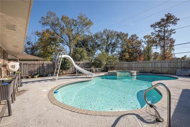 view of pool with a water slide, an in ground hot tub, and a patio