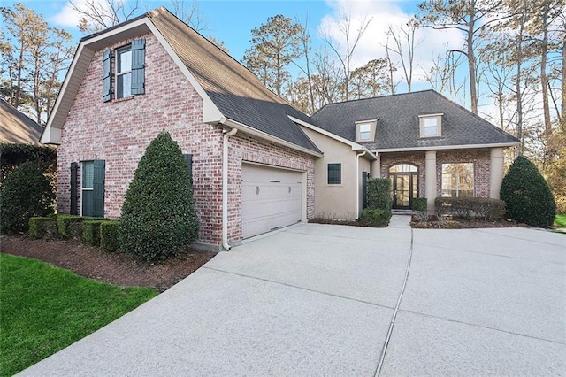 view of front of property featuring driveway, a shingled roof, an attached garage, and brick siding