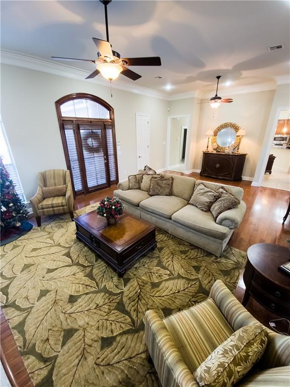 living room featuring hardwood / wood-style flooring, ceiling fan, and crown molding