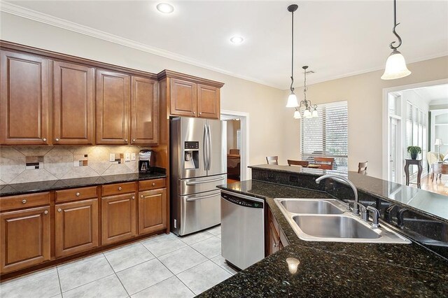 kitchen featuring appliances with stainless steel finishes, crown molding, sink, pendant lighting, and an island with sink