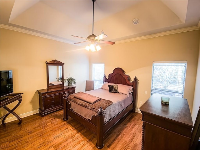 bedroom with hardwood / wood-style floors, ceiling fan, multiple windows, and a tray ceiling