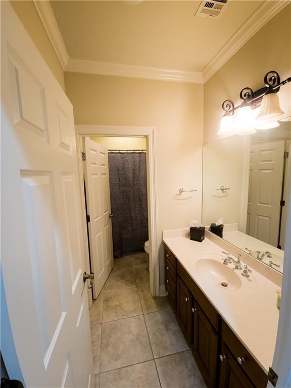 bathroom with tile patterned flooring, vanity, toilet, and ornamental molding