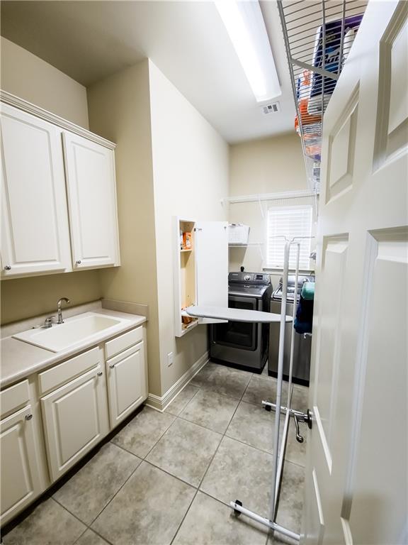 kitchen featuring sink, light tile patterned flooring, independent washer and dryer, stainless steel range with electric stovetop, and white cabinets