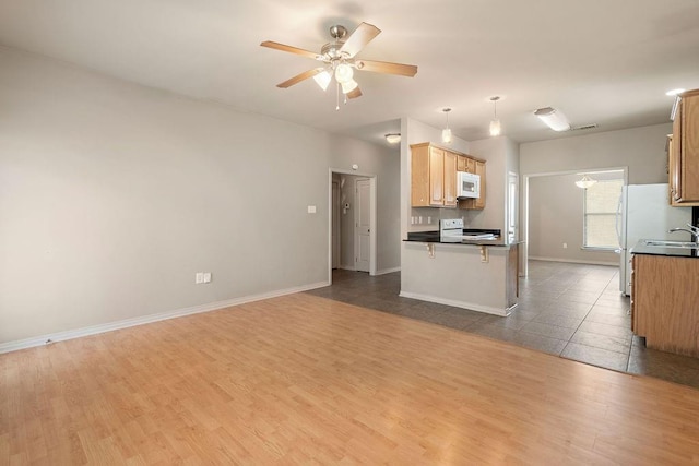 kitchen with hanging light fixtures, hardwood / wood-style flooring, ceiling fan, a kitchen bar, and range