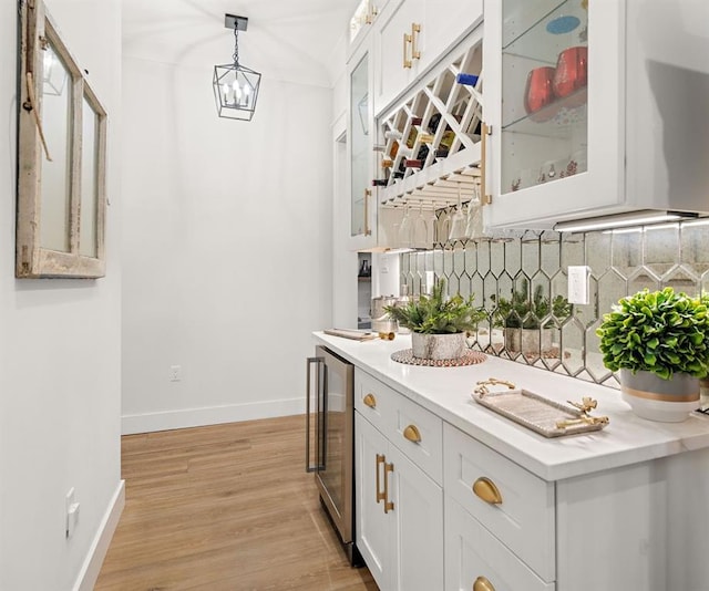 bar featuring wine cooler, light hardwood / wood-style floors, decorative backsplash, white cabinets, and decorative light fixtures