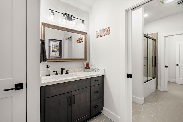 bathroom featuring enclosed tub / shower combo, tile patterned floors, and vanity