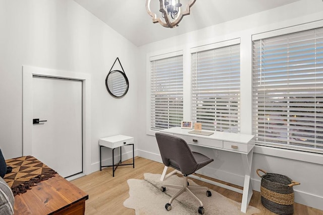 office space with an inviting chandelier, lofted ceiling, and light wood-type flooring