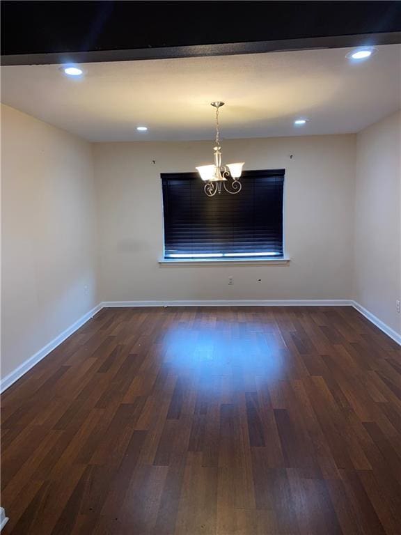 empty room featuring a chandelier and dark hardwood / wood-style floors