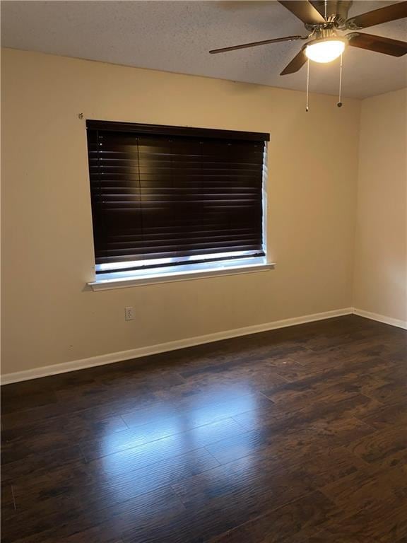 spare room with dark hardwood / wood-style floors, ceiling fan, and a textured ceiling