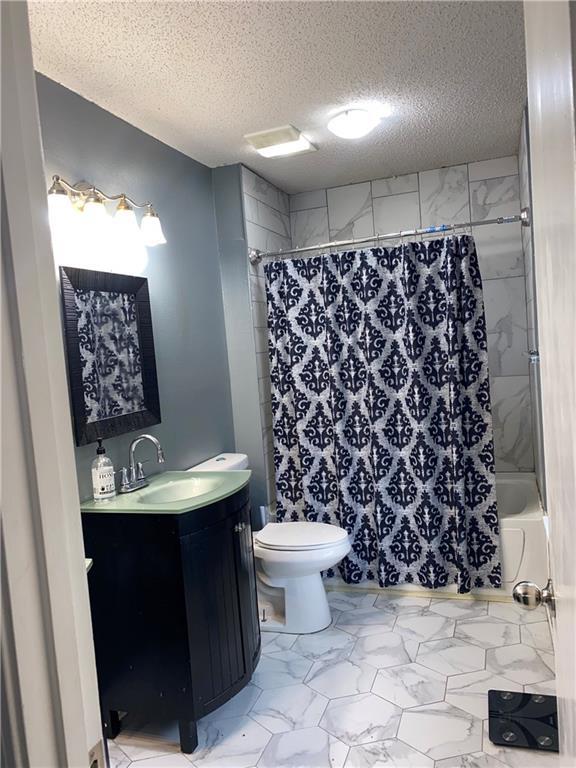 full bathroom with shower / bathtub combination with curtain, vanity, a textured ceiling, and toilet