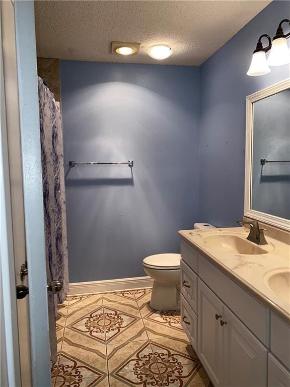 bathroom with tile patterned flooring, vanity, a textured ceiling, and toilet