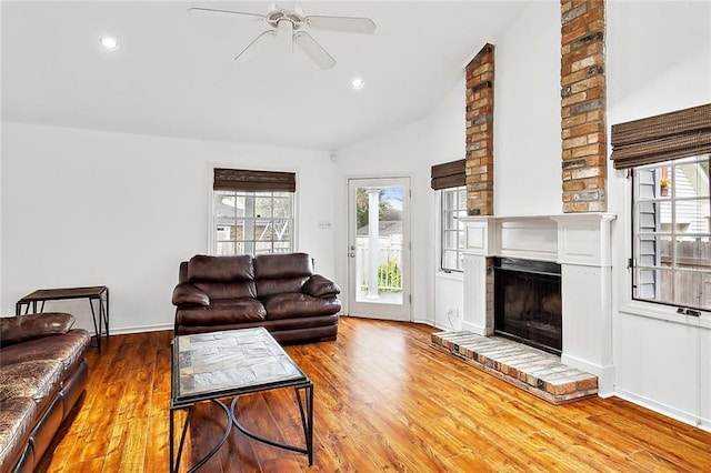 living room featuring a fireplace, hardwood / wood-style flooring, vaulted ceiling, and ceiling fan