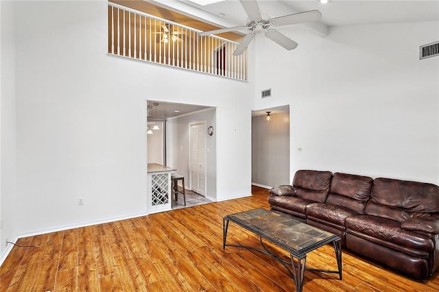 living room featuring ceiling fan with notable chandelier, hardwood / wood-style flooring, and high vaulted ceiling