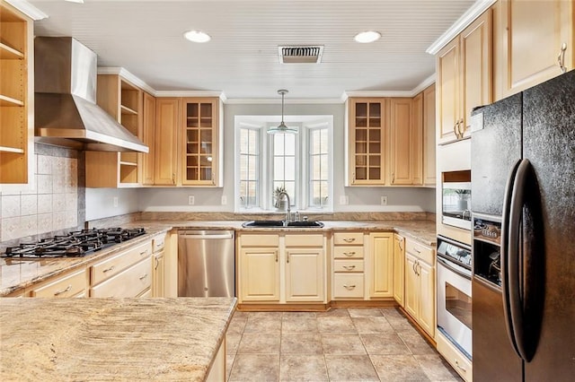 kitchen with wall chimney range hood, sink, light brown cabinetry, decorative light fixtures, and stainless steel appliances