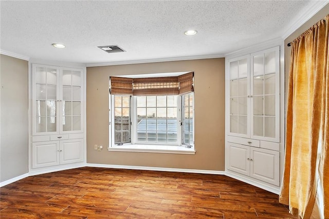 spare room with dark hardwood / wood-style flooring, ornamental molding, and a textured ceiling