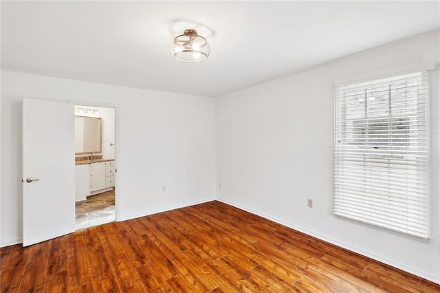 unfurnished bedroom with ensuite bath and light wood-type flooring