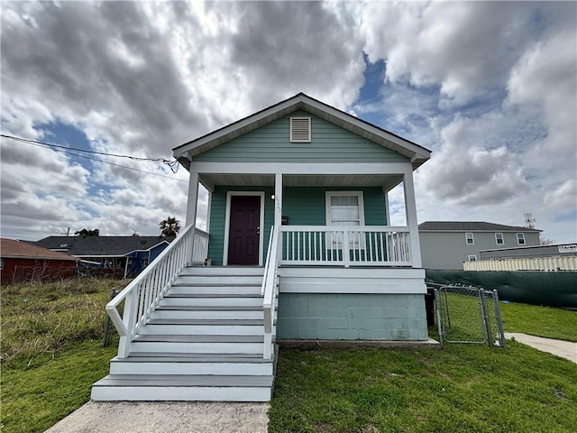 view of front of property with a porch, a front lawn, fence, and a gate