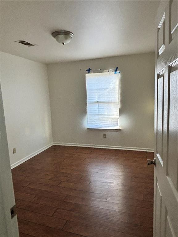 empty room with baseboards, visible vents, and hardwood / wood-style floors