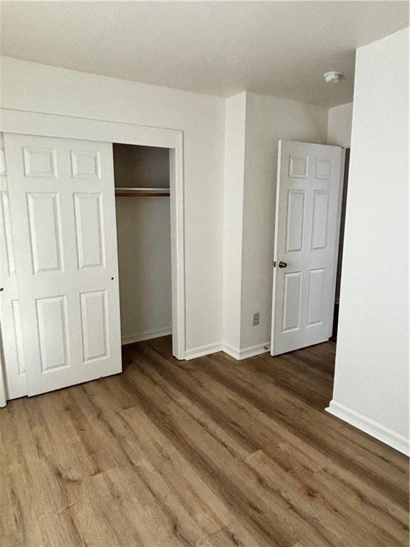 unfurnished bedroom featuring a closet, baseboards, and wood finished floors