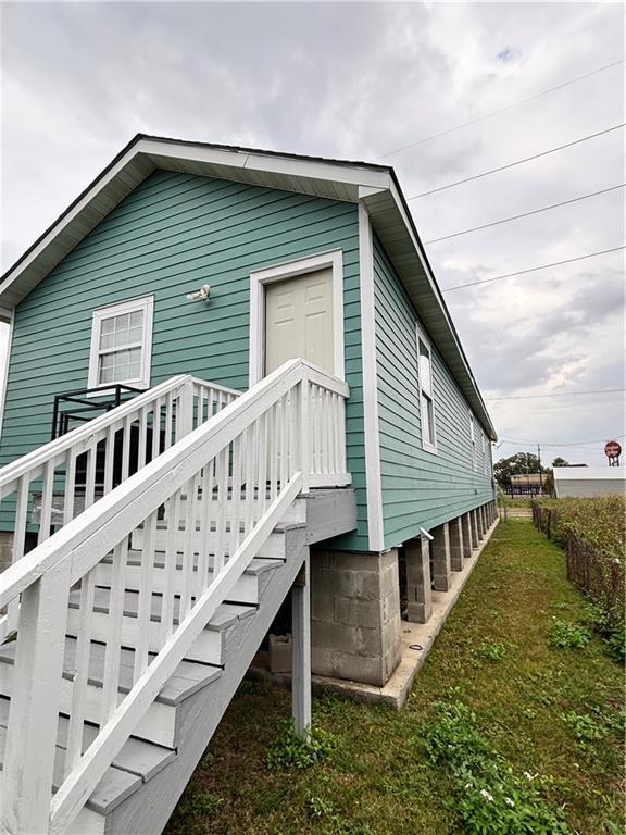 view of side of property with stairway and a lawn