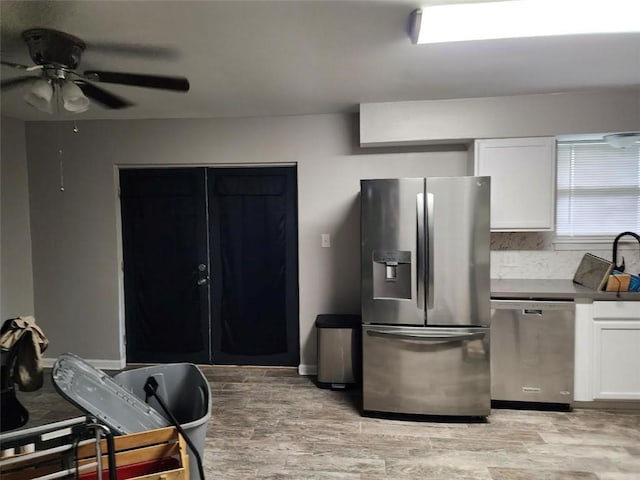 kitchen featuring light wood-type flooring, stainless steel appliances, ceiling fan, sink, and white cabinets