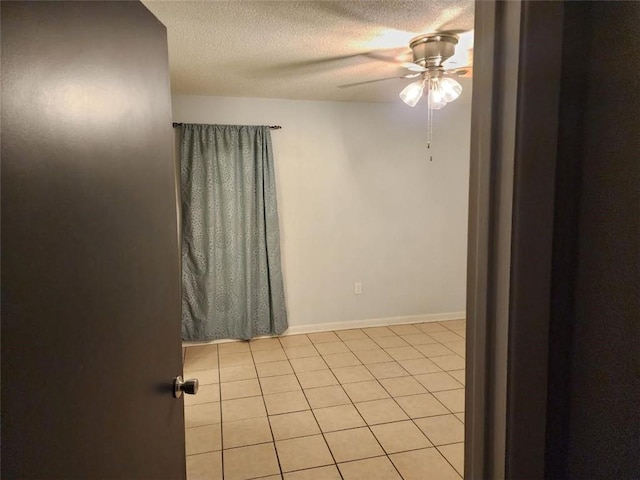 tiled spare room with a textured ceiling and ceiling fan