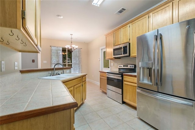 kitchen featuring pendant lighting, sink, light brown cabinets, and appliances with stainless steel finishes