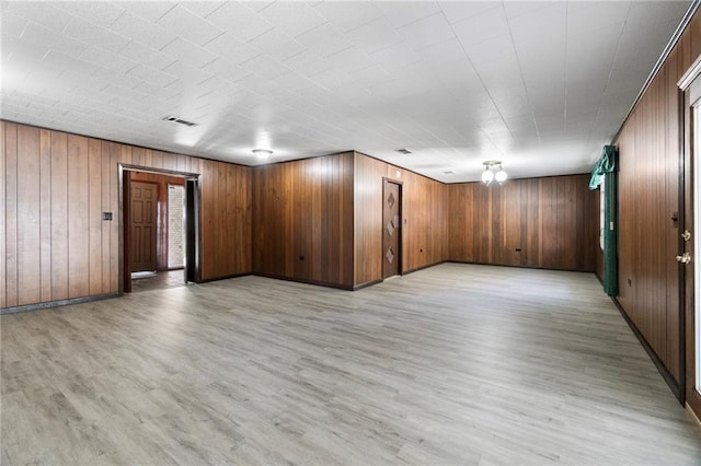 unfurnished room featuring light hardwood / wood-style floors and wooden walls