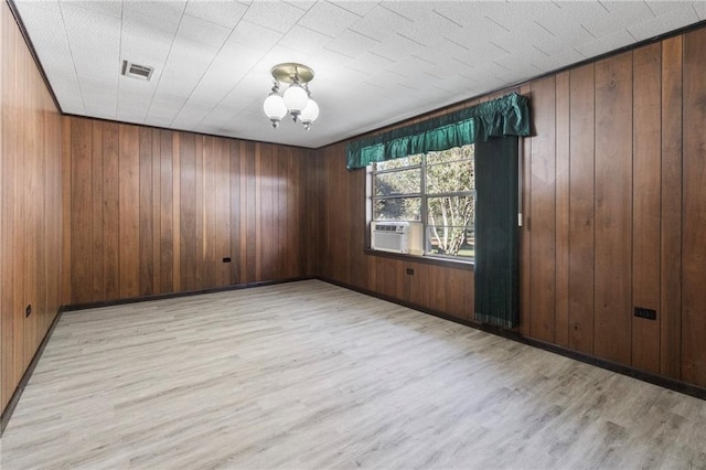 unfurnished room featuring light hardwood / wood-style flooring, cooling unit, and wooden walls