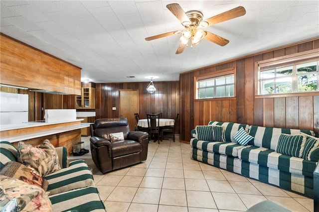 tiled living room featuring ceiling fan and wooden walls